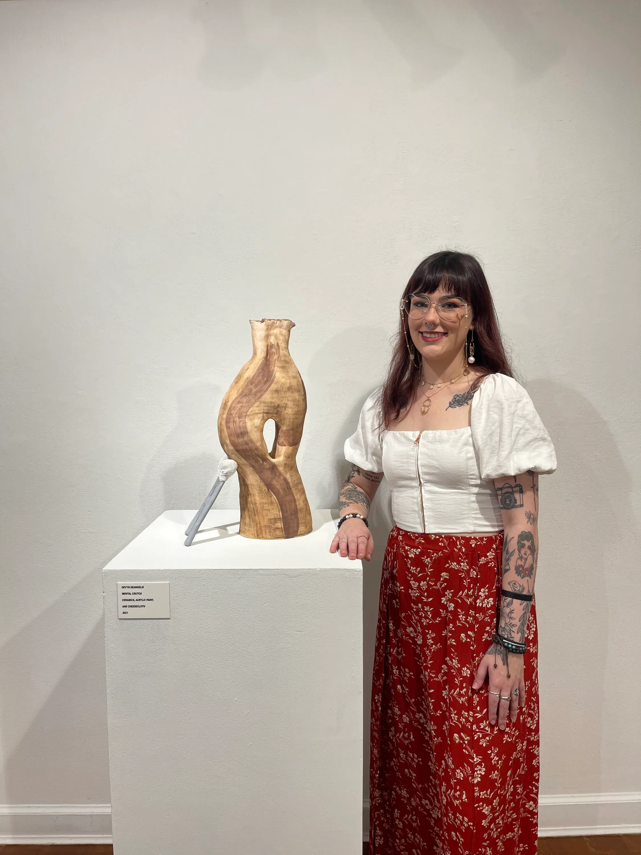 Devyn standing beside the ceramic sculpture Mental Crutch