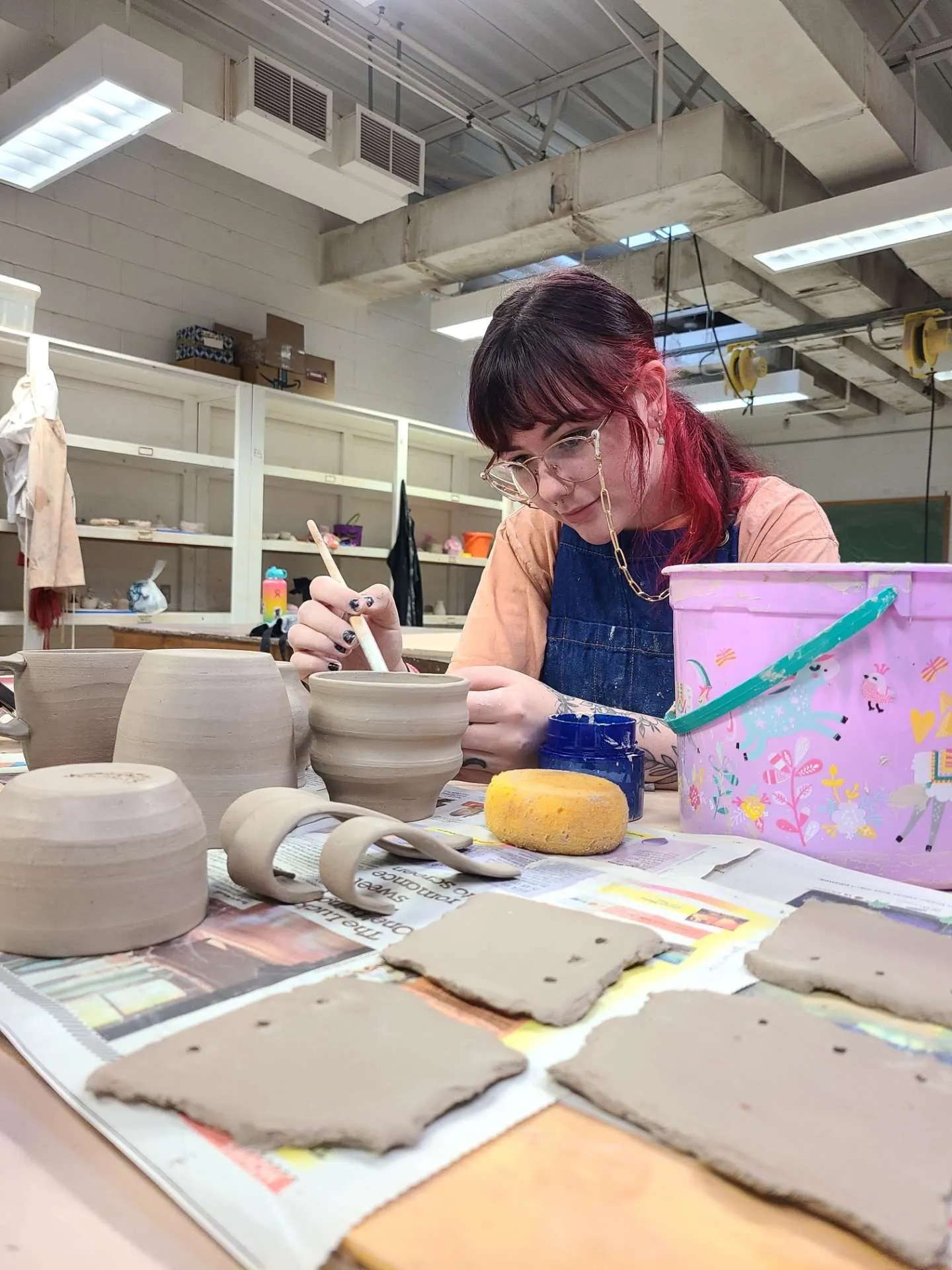Devyn painting ceramic vessels in the studio