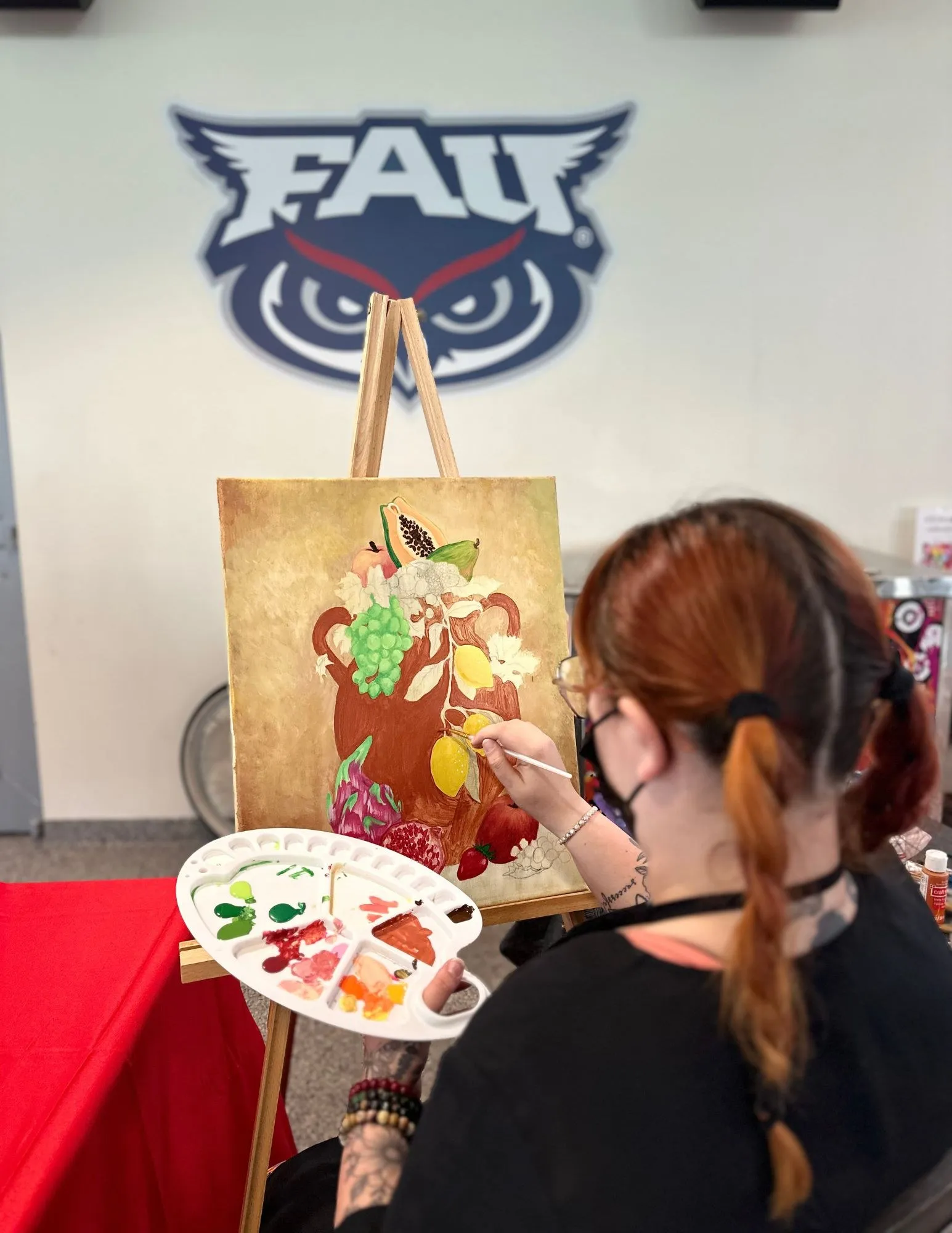 Devyn painting an owl illustration on a panel
